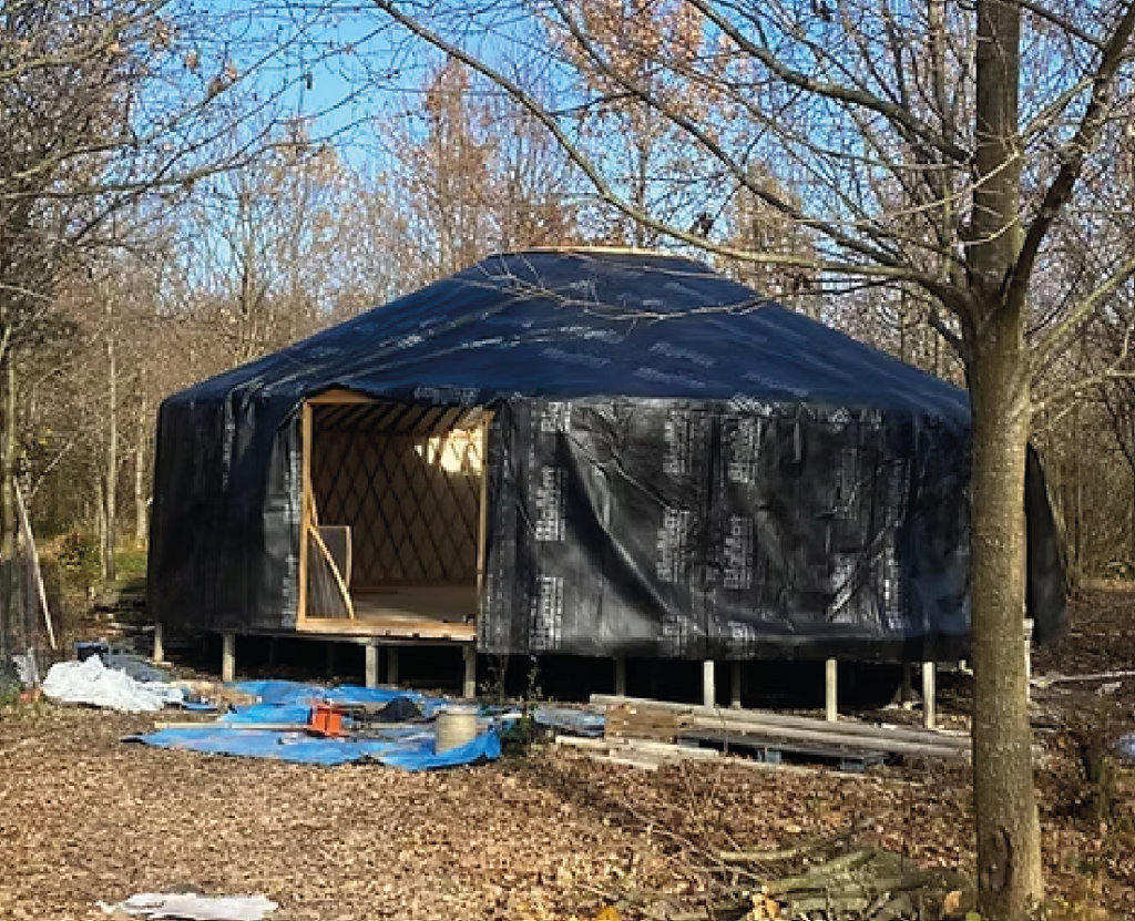 Yurta in costruzione con copertura in tela nera su piattaforma rialzata